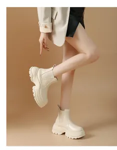Detail view of stylish cream platform Chelsea boots with chunky lug sole on model