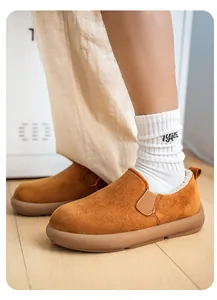 Close-up of men's tan suede slip-on snow boots with warm fur lining on wooden floor