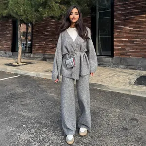 Full-body street style shot of women's gray ribbed knit wrap sweater and wide-leg trousers