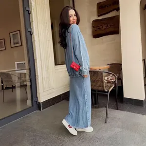 Model wearing a stylish light blue denim two-piece set with long skirt and zip-up jacket.