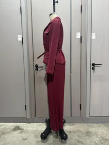 Vista lateral de un conjunto burdeos de blazer y falda plisada para mujer