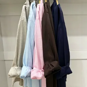 Detail of linen shirts in various colors hanging on a rack showing fabric texture.