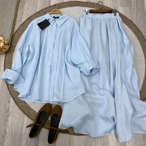 Flat lay view of women's light blue long-sleeve linen shirt and long maxi skirt set
