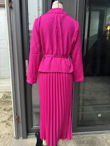 Vista trasera detallada de un conjunto de chaqueta fucsia y falda plisada en un maniquí.