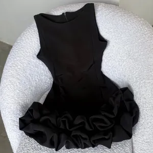 Detailed view of the intricate ruffled floral hem on a black sleeveless Hepburn style dress.