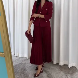 Detalle del elegante blazer burdeos con botones dorados y falda midi plisada a juego