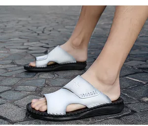 Vue détaillée de claquettes décontractées en cuir blanc pour hommes sur un pavé