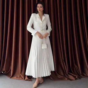Detalle de un conjunto elegante de blazer blanco con botones y falda larga plisada.