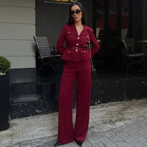 Modelo elegante posando con un blazer burdeos formal y pantalones anchos a juego