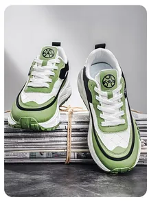 Zapatillas chunky dad modernas en verde y blanco con suela gruesa sobre una pila de diarios.