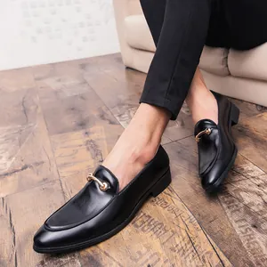 Primo piano di mocassini da uomo in pelle nera con fibbia in metallo dorato su pavimento.