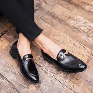 Primo piano di mocassini in pelle nera da uomo con fibbia dorata su pavimento legno