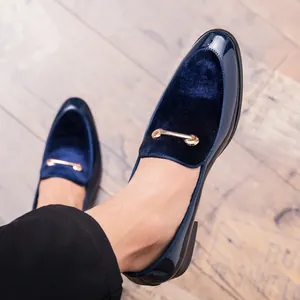 Primo piano di mocassini da uomo in velluto blu navy e vernice con fibbia in metallo.