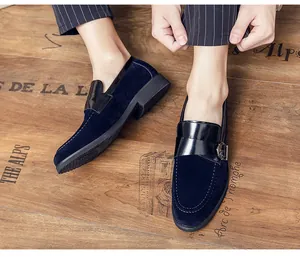 Close-up detail of navy blue suede loafers featuring black patent leather and metal buckle
