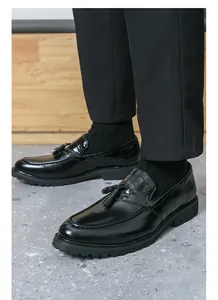 Detail view of men's black tassel loafers with embossed crocodile texture and thick sole