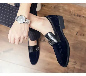 Close-up detail of navy blue suede loafers with black leather accents and buckle on foot
