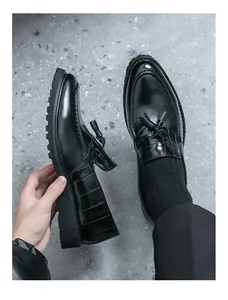 Detailed macro view of black tassel loafers featuring crocodile texture and thick lug soles