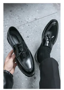 Detail shot of black leather tassel loafers showing texture and slip-on design for men