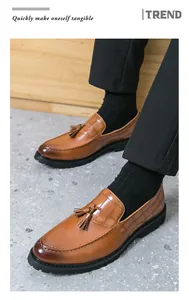 Close-up of stylish men's brown crocodile embossed tassel loafers with thick black soles.