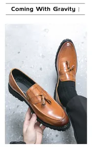 Brown leather tassel loafers with embossed crocodile texture shown in a close-up view