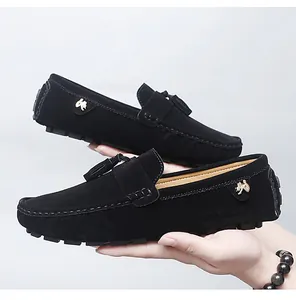Vue détaillée de mocassins en daim noir avec pompons et logo métallique sur le côté