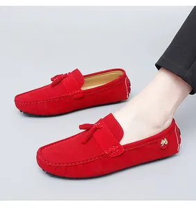 Détail de mocassins en daim rouge pour hommes avec des glands et un logo en métal