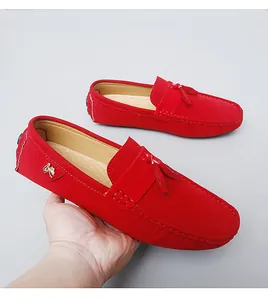 Vue détaillée de mocassins en daim rouge avec gland et emblème métallique décoratif