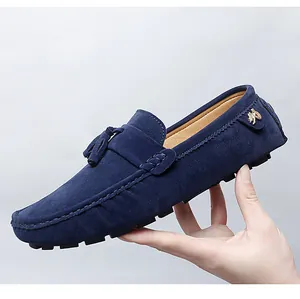 Vue détaillée des mocassins en daim bleu marine avec pompons et logo métallique chic.