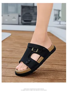 Seitenansicht der schwarzen Herrensandalen mit Schnalle auf Holz