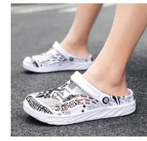 Close-up of white men's garden clogs with stylish newspaper print worn outdoors.
