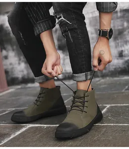 Close-up of man tying laces on olive green high-top outdoor Martin boots.