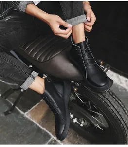 Detailed view of men's black high-top Martin boots worn by a model on a vintage motorcycle