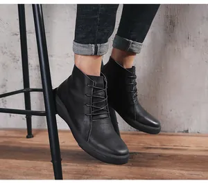 Detailed view of stylish black leather high-top Martin boots worn with denim jeans