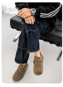 Lifestyle-Detail von braunen Herren-Wildleder-Slippern mit Schnalle und dunkler Denim-Jeans