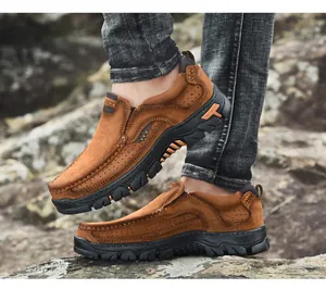 Vista lateral de zapatos de senderismo marrones para hombre en terreno rocoso natural.