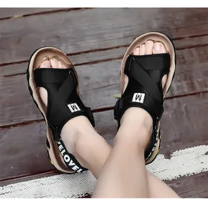 Nahaufnahme schwarzer Herren-Sportsandalen mit gekreuzten Riemen und weißer Aufschrift auf Holz.