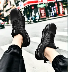 Detailed view of men's black fly-knit blade sneakers with breathable mesh on street