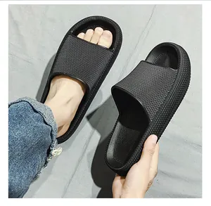 Top view of thick-soled black slide slippers shown worn on feet and held by hand