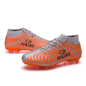 Detalle de botas de fútbol de caña alta con diseño de ondas naranjas y plateadas