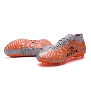 Detalle lateral de botas de fútbol de caña alta gris y naranja con tacos AG muy resistentes