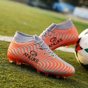 Primer plano detallado de botas de fútbol de caña alta con rayas naranjas y grises y tacos AG.