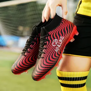 Primer plano de botas de fútbol de caña alta con rayas rojas y negras en campo