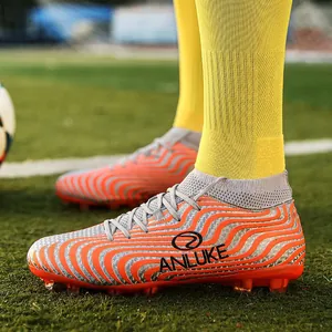 Vista detallada de botas de fútbol de caña alta con patrones ondulados naranjas.