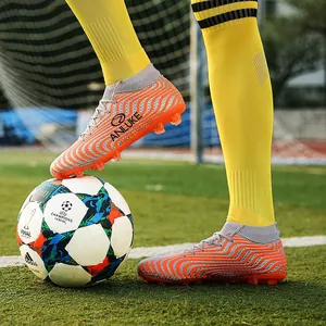 Botas de fútbol de caña alta naranjas con patrón de ondas en césped artificial