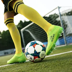 Botas de fútbol de caña alta verde neón en acción en el campo con suela de tacos AG