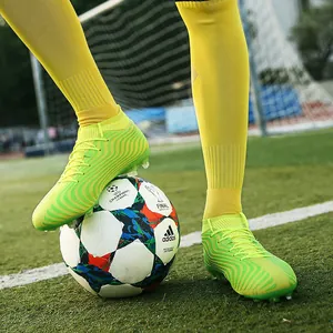 Detalle de botas de fútbol de caña alta amarillo fluorescente en campo de césped artificial