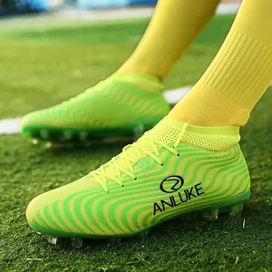 Primer plano de botas de fútbol AG amarillas altas con diseño de ondas en césped.