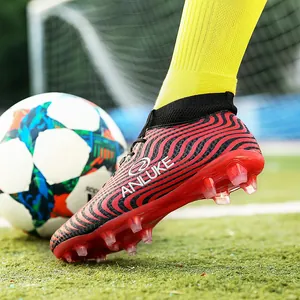 Primer plano detallado de botas de fútbol de caña alta con tacos AG en césped artificial