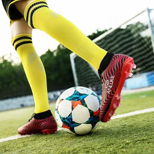 Foto de acción de botas de fútbol de caña alta a rayas rojas y negras con tacos AG.