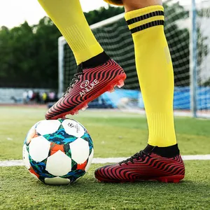 Botas de fútbol profesionales de caña alta con patrón ondulado rojo en césped.